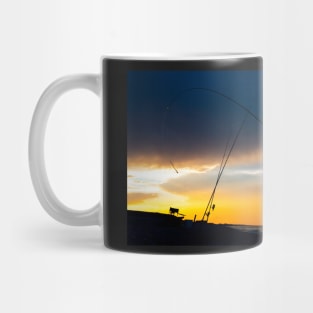 Fisherman cast fishing rods on the seashore at a dramatic sunset. Mug